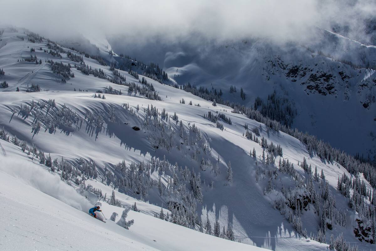 A skier glides through powder at Revelstoke Mountain Resort with big mountain views in the backdrop.
